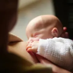 Un neonato dorme serenamente mentre viene allattato. Un momento intimo che fa riflettere su cosa mangiare in allattamento per il benessere di entrambi.