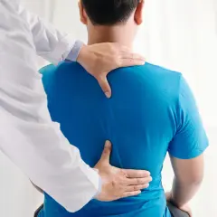 Un osteopata esamina la schiena di un paziente, aiutando a trovare sollievo dal mal di schiena.