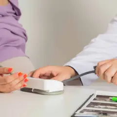 Lekarz mierzy ciśnienie ciężarnej pacjentce, monitorując jej stan pod kątem ryzyka **preeklampsji**.