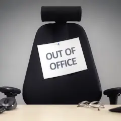 Puste biurowe krzesło z kartką "OUT OF OFFICE". Czas na zasłużone święta w sierpniu!