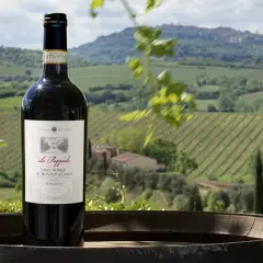 Bottiglia di vino nobile di Montepulciano DOCG su un barile, con vigneti e colline toscane sullo sfondo.