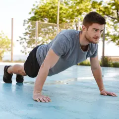 Mężczyzna wykonuje pompki na biceps na zewnątrz.