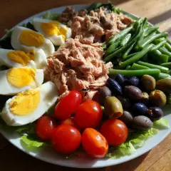 En härlig sallad nicoise med ägg, tonfisk, gröna bönor, tomater och oliver på en bädd av sallad.