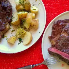 Dwa soczyste steki z ziemniakami i koperkiem. Idealny sos do steka podkreśla smak dania.