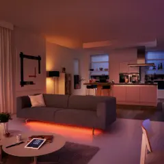 Sofá moderno con iluminación led ambiental. Cocina integrada, arte abstracto y silla naranja. Las led caracteristicas crean una atmósfera acogedora.