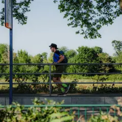 Mann mit Rucksack und Hut läuft auf einem Weg in Mannheim, umgeben von Bäumen und Grün.
