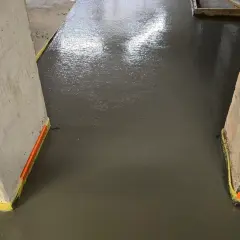 Świeżo wylana, mokra wylewka betonowa między dwoma filarami.