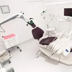 Nowoczesny gabinet stomatologiczny z fotelem, mikroskopem i sprzętem.