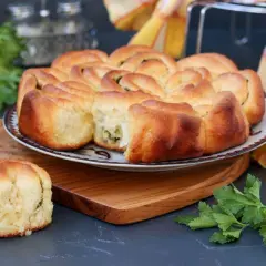 Puszysty chlebek ziołowy z Thermomixa, upieczony na złoto, z zieloną natką pietruszki obok.