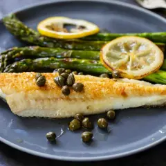Sogliola in friggitrice ad aria, dorata e succulenta, servita con asparagi croccanti, capperi e fette di limone.
