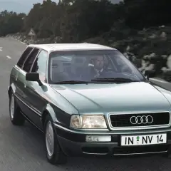 Mężczyzna w garniturze jedzie zielonym Audi 1.9 TDI po krętej drodze.