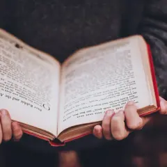 Mani che tengono un libro aperto con testo in inglese, forse uno dei tanti libri premiati che raccontano storie avvincenti.
