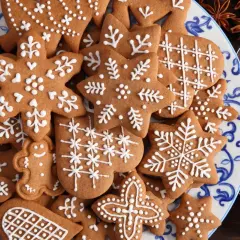Talerz pełen pierniczków staropolskich (długodojrzewających) ozdobionych białym lukrem. Wśród nich gwiazdki, płatki śniegu i ludziki.