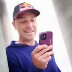 Mężczyzna w czapce Red Bull trzyma telefon z wzorzystym etui. Wzory na telefonie są czerwono-niebieskie.