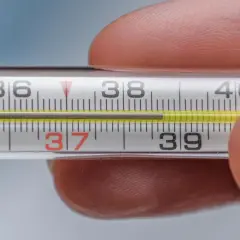 Termometr pokazuje podwyższoną temperaturę ciała, około 37,5 stopnia Celsjusza.