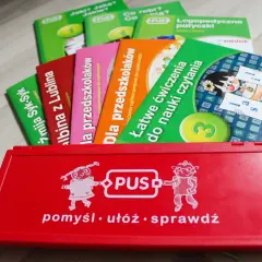 Czerwone pudełko z zabawkami edukacyjnymi PUS i kolorowe książeczki.