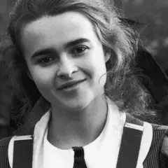 Młoda Helena Bonham Carter z burzą loków i figlarnym uśmiechem, w stroju przypominającym szkolny mundurek.