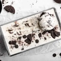 Selbstgemachtes Oreo Eis in einer Metallform, mit einem Löffel und zerbrochenen Keksen garniert. Perfekt für alle, die Oreo Eis selber machen wollen.