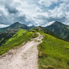 Szlak na Ornaka z Doliny Kościeliskiej. Kręta ścieżka prowadzi przez zielone zbocza Tatr pod burzowe niebo.