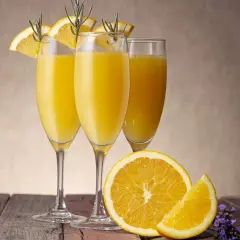 Tre glas med en gyllene drink med cava, garnerade med apelsinskivor och rosmarin. En apelsin och lavendel på träbordet.