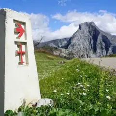 Señal del camino lebaniego, indicando la ruta. El paisaje montañoso sugiere la dificultad del camino.