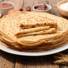 Una pila de crepes dorados, con ingredientes como leche, huevos y harina, evocan el origen de los crepes, un manjar sencillo y delicioso.
