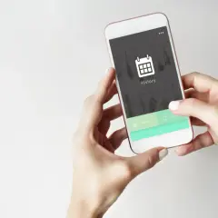 Dłonie trzymają smartfon z ikoną kalendarza i napisem "History". Aplikacja pokazuje historię przeglądania.