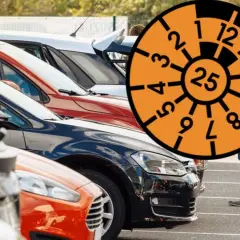 Rząd samochodów na parkingu z pomarańczową tarczą z numerami i cyfrą 25.