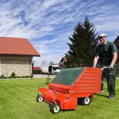 Mężczyzna z wertykulatorem na trawniku. Wertykulacja trawnika jesienią lub wiosną to klucz do zdrowego ogrodu.