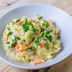 En skål med krämig potatissallad, toppad med purjolök. Den här ser ut att vara den godaste potatissalladen!