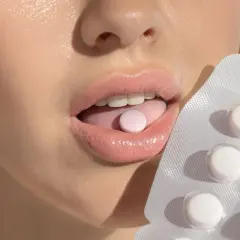Usta z tabletką na języku i opakowaniem. Probiotyk na nieprzyjemny zapach z ust dla świeżego oddechu.
