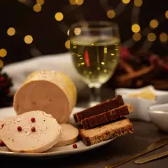 Tranche de vin foie gras sur une assiette, avec du pain d'épices et un verre de vin blanc. Ambiance festive.