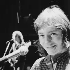 Chris Norman z mikrofonem na scenie, w tle inny muzyk.