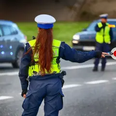 Policjantka kieruje ruchem, trzymając tarczę. Kierowcy powinni znać taryfikator mandatów, by uniknąć nieprzyjemności.