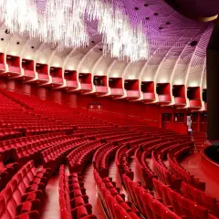 Interno di un teatro moderno con file di poltrone rosse e un soffitto decorato. Uno dei teatri più grandi d'Italia, pronto ad accogliere il pubblico.