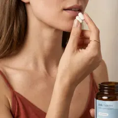 Frau nimmt Zinktabletten ein, um die Zinkaufnahme zu verbessern.