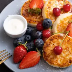 Pyszne placuszki z twarogu, idealne na śniadanie z airfryer, podane z owocami i śmietaną.