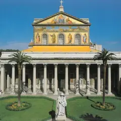 La **cattedrale San Paolo Roma** vista dal cortile con statue, palme e un prato curato.
