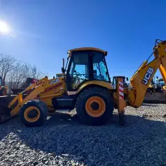 Żółta koparko-ładowarka JCB na placu budowy, gotowa do pracy.