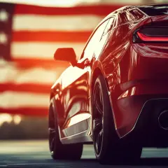 Błyszczący, czerwony samochód sportowy, symbol amerykańskich samochodów, na tle flagi USA.