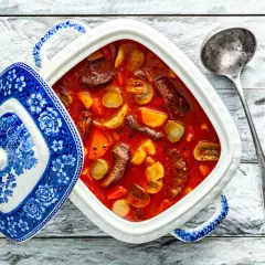 Tradycyjny zupa strogonow w białej wazie z niebieskimi zdobieniami, obok metalowa chochla.