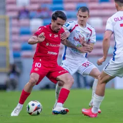Piłkarze Widzewa Łódź i Górnika Zabrze walczą o piłkę. Czerwona koszulka z numerem 10 i biała z numerem 16.