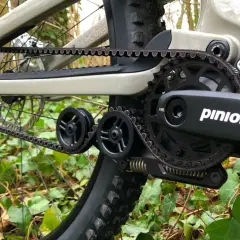 Close-up of a belt drive mountain bike's drivetrain, featuring a Pinion gearbox and Gates Carbon Drive belt, ready for off-road adventures.