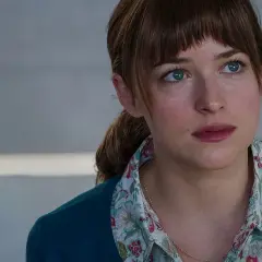 Dakota Johnson with blue eyes and brown hair, wearing a floral shirt and teal cardigan.