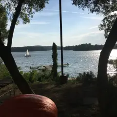 Sielankowy widok na jezioro w Sierakowskim Parku Krajobrazowym. Żaglówka sunie po falach, a na brzegu czeka ławka i dynia.