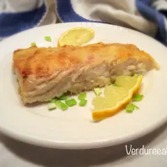 Un filetto di pesce persico cotto in padella, guarnito con spicchi di limone e erba cipollina. Perfetto per una ricetta pesce persico in padella al limone leggera e gustosa.