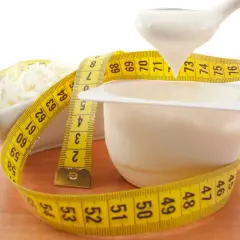Biały jogurt i twaróg owinięte miarką. Czy od białka się tyje? Zdrowa dieta to klucz do sukcesu.