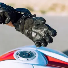 Persona se ajusta guantes de moto negros. Es obligatorio llevar guantes en moto para protegerse.