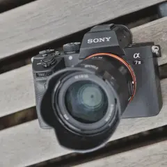 Sony A7 III test na drewnianej ławce. Aparat z obiektywem leży na deski.