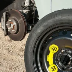 Rueda de galleta de repuesto junto al disco de freno de un coche, lista para ser instalada.